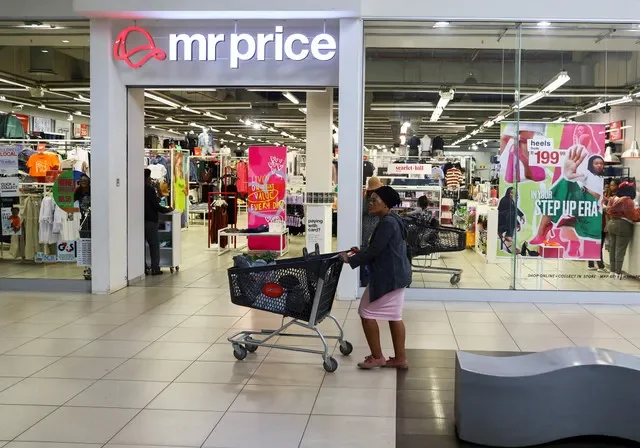 A customer with a shopping cart stands outside a Mr Price storefront at the Trade Route Mall in Lenasia, near Johannesburg, South Africa, in early 2023. REUTERS/Siphiwe Sibeko/File Photo
