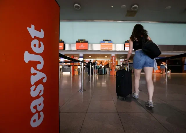 A traveler passes by the easyJet branding at a check-in counter in Barcelona's Josep Tarradellas Barcelona-El Prat Airport during a period of industrial action. REUTERS/Albert Gea