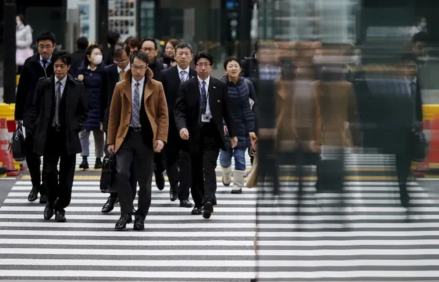 Personas se reflejan en una pared mientras cruzan una calle en el distrito de negocios de Tokio, Japón, el 22 de febrero de 2016. REUTERS/Toru Hanai