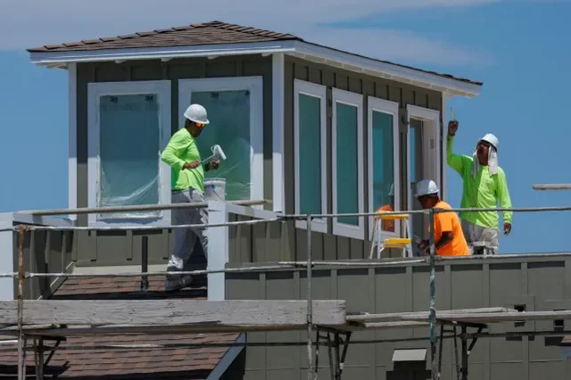 Construction workers apply paint to a residential development in Carlsbad, California, in July 2025.