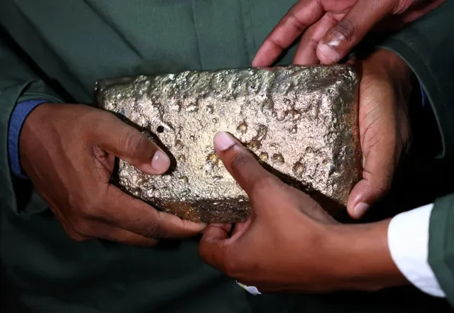 Visitantes sostienen una barra de oro en bruto dentro de una sala de procesamiento en la planta de procesamiento Ezulwini de Sibanye Stillwater cerca de Westonaria, al oeste de Johannesburgo, Sudáfrica, el 17 de marzo de 2026. REUTERS/Siphiwe Sibeko