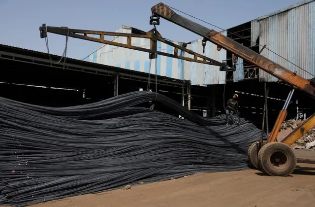 A worker unloads steel reinforcement bars at a production facility in Gujarat, India, during April 2025.