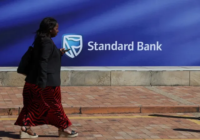 A pedestrian passes the branding of Standard Bank during the 2024 Investing in African Mining Indaba held in Cape Town. REUTERS/Esa Alexander