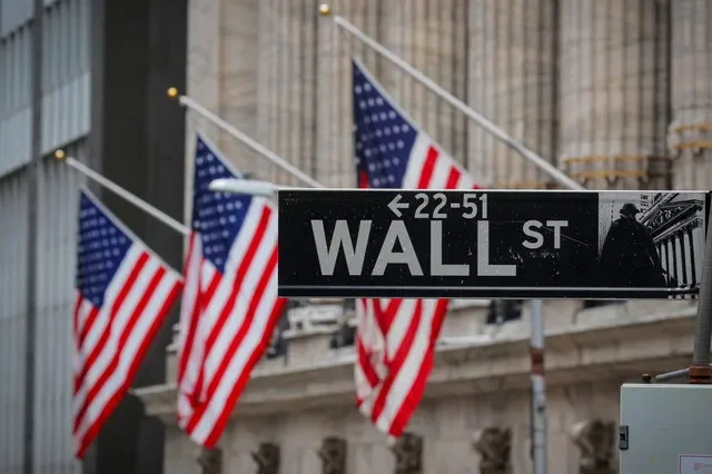 A street sign for Wall St. is visible in front of the New York Stock Exchange building in New York City, as photographed in February 2021. REUTERS/Brendan McDermid