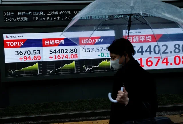 مشاة يمرون بجانب لوحة عرض لأسعار الأسهم تظهر مؤشر توبكس ونيكي وسعر صرف الين الياباني مقابل الدولار الأمريكي خارج شركة وساطة في طوكيو، اليابان، 10 مارس 2026. رويترز/كيم كيونغ هون