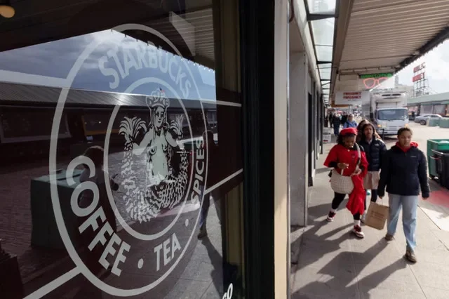 O logotipo original da Starbucks em uma vitrine enquanto pessoas passam por uma das primeiras lojas no Pike Place Market em Seattle, Washington, EUA, em 12 de novembro de 2025. REUTERS/Matt Mills McKnight