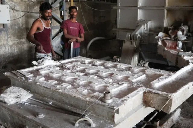 Trabalhadores observam o alumínio derretido fluir através de uma matriz para fabricar barras dentro de uma fábrica de extrusão de alumínio em Dahegam, Índia, em 19 de março de 2026. REUTERS/Amit Dave