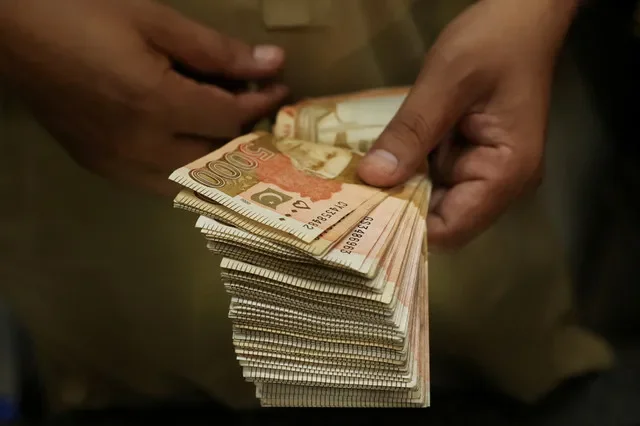 صورة أرشيفية: تاجر يعد أوراق النقد من الروبية الباكستانية في كشك لتداول العملات في بيشاور، باكستان، 29 يوليو 2025. تصوير: فياض عزيز/رويترز
