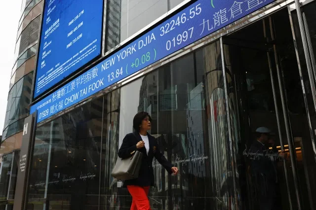 A pedestrian passes a financial display showing market indices in Hong Kong's Central district. Photo by Tyrone Siu/REUTERS