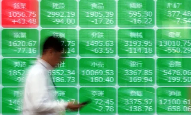 東京の証券会社前で株価指数が表示されたスクリーンを通り過ぎる男性。2026年3月30日撮影。REUTERS/Issei Kato