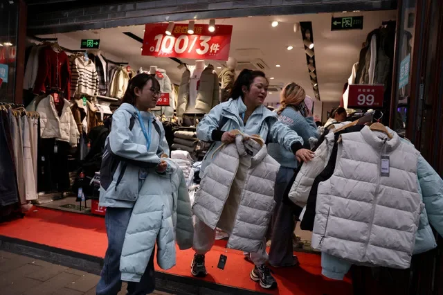 2025年10月18日,中国北京的一家商店内,工作人员正在促销打折夹克。REUTERS/Tingshu Wang