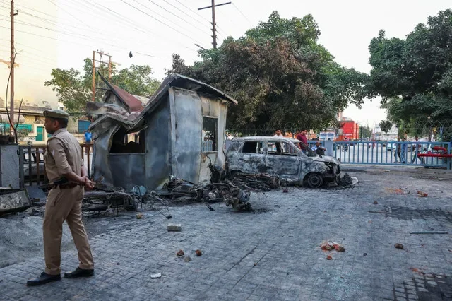 Un oficial de policía camina junto a un vehículo incendiado durante las manifestaciones de trabajadores en Uttar Pradesh, India, el 13 de abril de 2026. REUTERS/Anushree Fadnavis