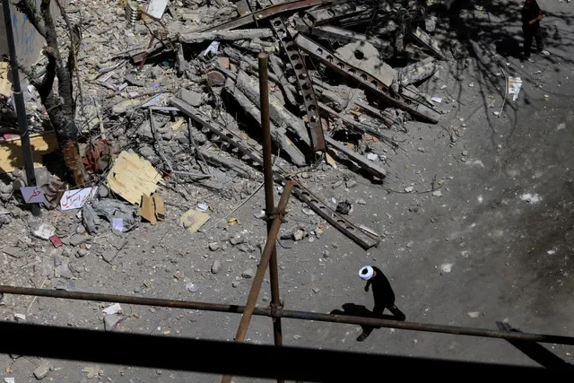 A cleric walks near a residential building damaged by a strike on March 4, in Tehran, Iran. REUTERS/Thaier Al Sudani