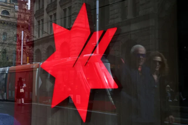 FOTO DE ARCHIVO: El logotipo de National Australia Bank (NAB) se refleja en una sucursal mientras la gente camina por el distrito financiero de Sídney, Australia. REUTERS/Hollie Adams