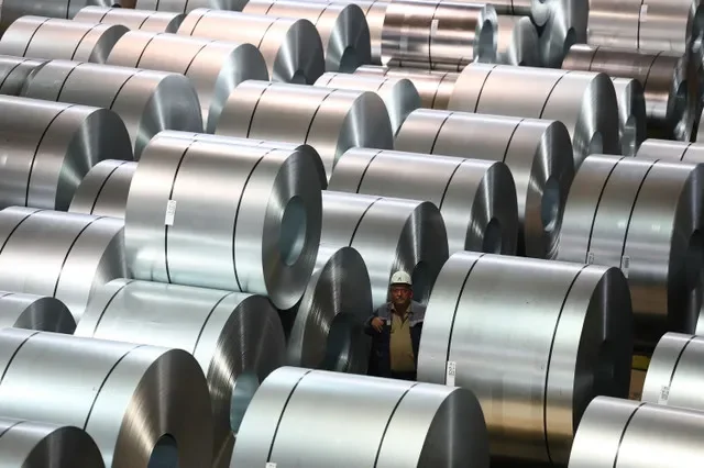 A worker navigates through rows of steel coils at a ThyssenKrupp distribution center in Duisburg, Germany, captured in late 2023. REUTERS/Wolfgang Rattay