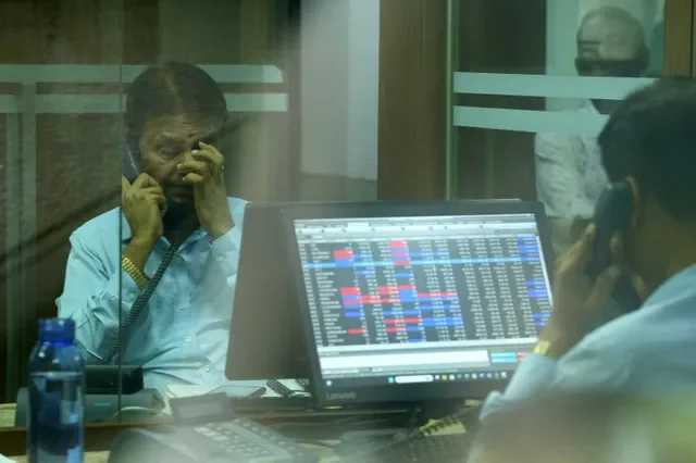 A stockbroker in Mumbai monitors market movements on his terminal while conducting a phone call at a brokerage firm. REUTERS/Hemanshi Kamani