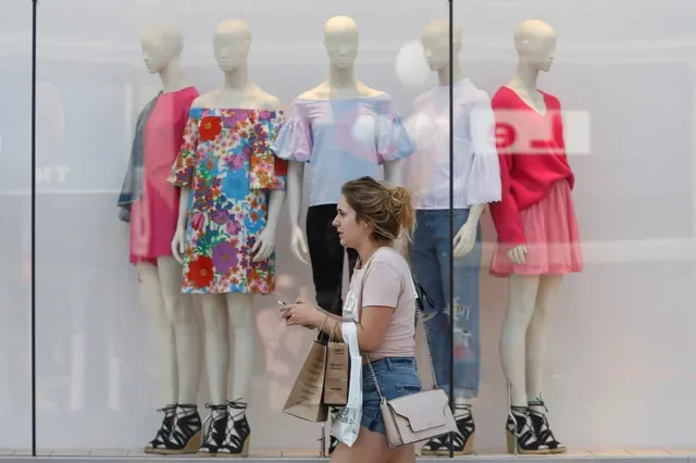 A shopper walks past a retail storefront in Ottawa, reflecting the steady pace of consumer activity in the Canadian market.