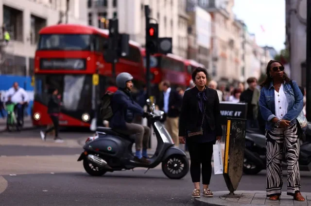 Vehicles and pedestrians navigate the busy intersection of Oxford Street in London, England. REUTERS/Hannah McKay