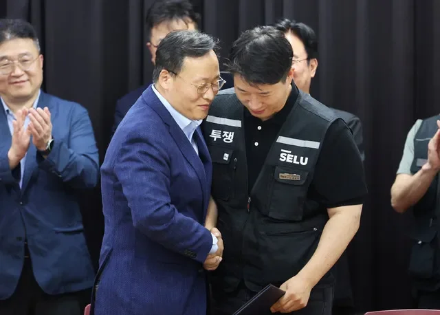 Choi Seung-ho, head of Samsung Electronics union and Yeo Myung-koo, head of the People Team under Samsung's Device Solutions division and the company's chief management negotiator, shake hands after reaching a tentative pay deal in Suwon, South Korea, May 20, 2025. Yonhap via REUTERS