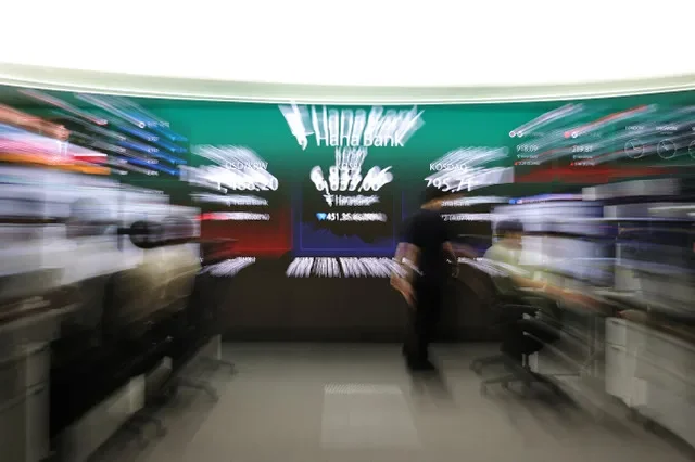A currency dealer walks in front of an electronic board displaying the exchange rate between the U.S. dollar and South Korean won, the Korea Composite Stock Price Index (KOSPI) and the Korea Securities Dealers Automated Quotations (KOSDAQ) at the dealing room of a bank in Seoul, South Korea, July 16, 2026. REUTERS/Kim Hong-Ji