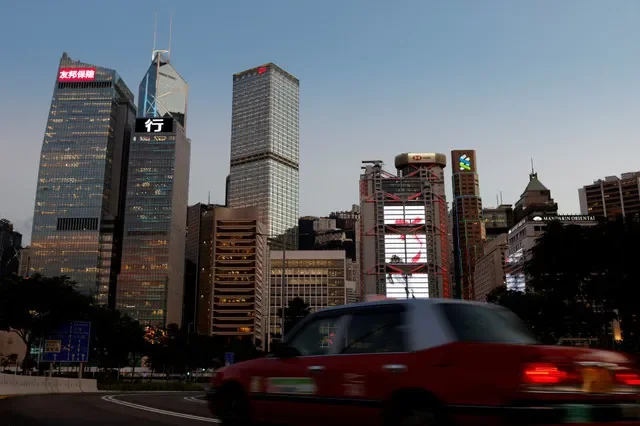 FILE PHOTO: A taxi drives in front of skyscrapers at the central business district in Hong Kong, China August 17, 2021. Picture taken August 17, 2021. REUTERS/Tyrone Siu/File Photo
