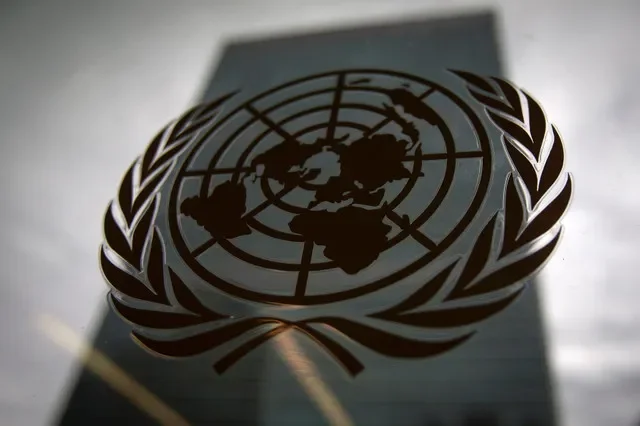 O edifício da sede das Nações Unidas é visto através de uma janela com o logótipo da ONU em primeiro plano no bairro de Manhattan, em Nova Iorque, a 15 de agosto de 2014. REUTERS/Carlo Allegri