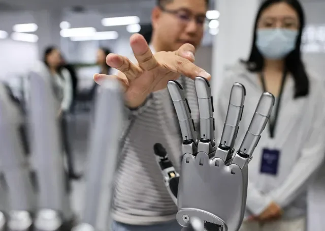 Foto de arquivo: Um homem toca numa mão robótica exibida na área de demonstração no escritório da Linkerbot, em Pequim, China, 27 de abril de 2026. REUTERS/Maxim Shemetov/Foto de arquivo