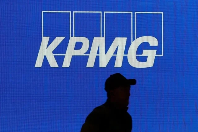 FILE PHOTO: オーストラリア・シドニーにある会社の本社に掲げられたKPMGのロゴの脇を歩く男性、2026年7月23日。REUTERS/Hollie Adams/File Photo