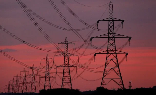 FILE PHOTO: The sun rises behind electricity pylons near Chester, northern England October 24, 2011. REUTERS/Phil Noble/File Photo
