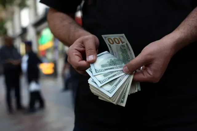 A currency dealer holds one-hundred-dollar bills in Tehran, Iran, May 2, 2026. Majid Asgaripour/WANA (West Asia News Agency) via REUTERS