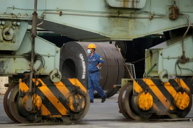 Um funcionário passa por bobinas de aço em um porto durante uma visita de imprensa organizada pelo governo à Baoshan Iron & Steel Co., Ltd. (Baosteel), subsidiária do China Baowu Steel Group, em Xangai, China, em 16 de setembro de 2022. REUTERS/Aly Song