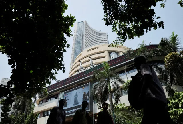 FILE PHOTO: Men walk past a screen displaying market results outside the Bombay Stock Exchange (BSE) in Mumbai, India, April 7, 2025. REUTERS/Francis Mascarenhas/File Photo