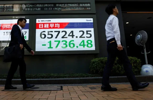 2026年8月19日,日本東京一家券商外,行人走過顯示日經平均指數的行情看板。REUTERS/Manami Yamada