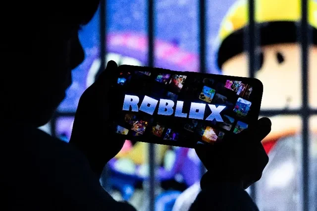 เด็กชายโพสท่าถ่ายรูปขณะถือสมาร์ตโฟนหน้าจอแสดงตัวละครของ Roblox วิดีโอเกมสำหรับเด็กของสหรัฐฯ ในภาพประกอบเมื่อวันที่ 8 ธันวาคม 2025 REUTERS/รามิล ซิตดิคอฟ/ภาพประกอบ