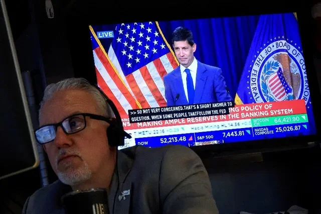 FILE PHOTO: A trader works, as a screen broadcasts a press conference by U.S. Federal Reserve Chair Kevin Warsh following the Fed rate announcement, on the floor of the New York Stock Exchange in New York City, U.S., July 29, 2026. REUTERS/Brendan McDermid/File Photo