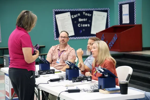 Poll workers talk to a voter inside Brown Elementary School in south Reno during primary voting on June 9, 2026.
