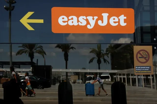 Passengers reflected on a glass with an Easyjet logo on it walk at Josep Tarradellas Barcelona-El Prat Airport during an Easyjet's cabin crew strike, in Barcelona, Spain, July 1, 2022. REUTERS/Albert Gea