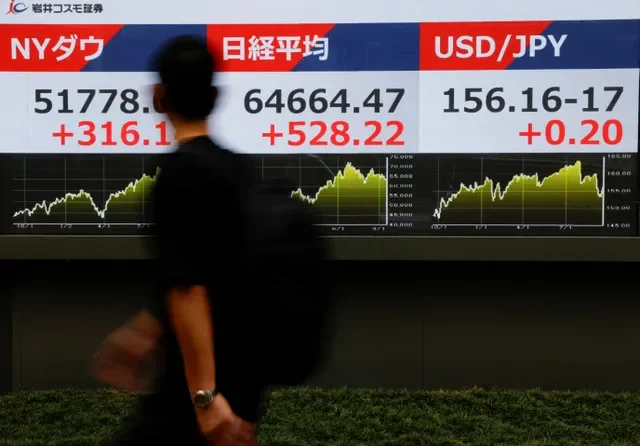 Um pedestre passa em frente a um painel eletrônico que exibe a média de ações do Nikkei, o Dow Jones Industrial Average e a taxa de câmbio entre o dólar americano e o iene japonês, do lado de fora de uma corretora em Tóquio, Japão, em 18 de setembro de 2026. REUTERS/Manami Yamada