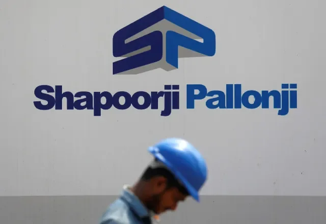 A construction worker walks past a hoarding of Indian conglomerate Shapoorji Pallonji Group on the outskirts of Mumbai, India April 17, 2018. REUTERS/Francis Mascarenhas