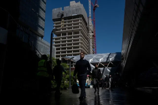 Người lao động đi bộ qua khu Canary Wharf với công trường xây dựng ở phía sau tại London, Anh, ngày 9 tháng 6 năm 2026. REUTERS/Chris J. Ratcliffe