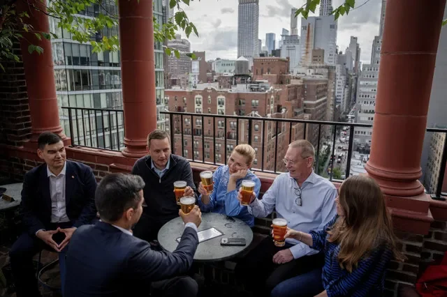 A primeira-ministra da Dinamarca, Mette Frederiksen, o primeiro-ministro da Groelândia, Jens-Frederik Nielsen, e o ministro das Relações Exteriores da Groelândia, Múte B. Egede, tomam uma cerveja com delegações em um bar em Manhattan após a assinatura do acordo em Nova York, EUA, em 22 de setembro de 2026. Ritzau Scanpix/Mads Claus Rasmussen/via REUTERS
