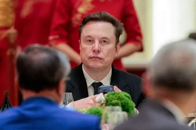 2026年5月14日、中国・北京の人民大会堂で、ドナルド・トランプ米大統領および中国の習近平国家主席との公式晩餐会に出席するため携帯電話を手にして到着したTeslaのイーロン・マスク最高経営責任者(CEO)。ロイター/エヴァン・ヴッチ