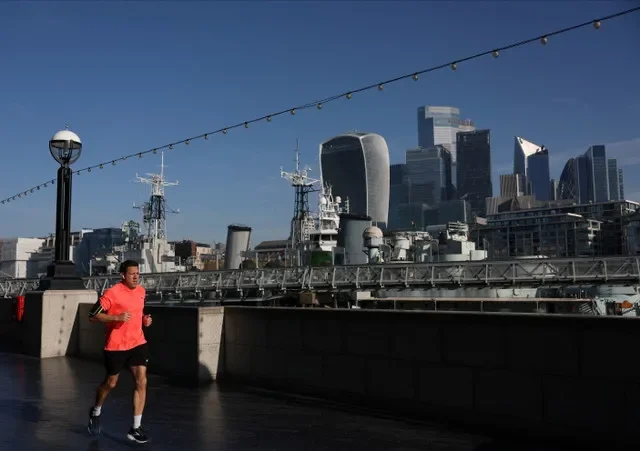 資料写真:2025年4月11日、英国ロンドンで、ロンドン金融街シティ・オブ・ロンドンの超高層ビル群を背にテムズ河南岸を走る男性。ロイター/イザベル・インファンテス/資料写真