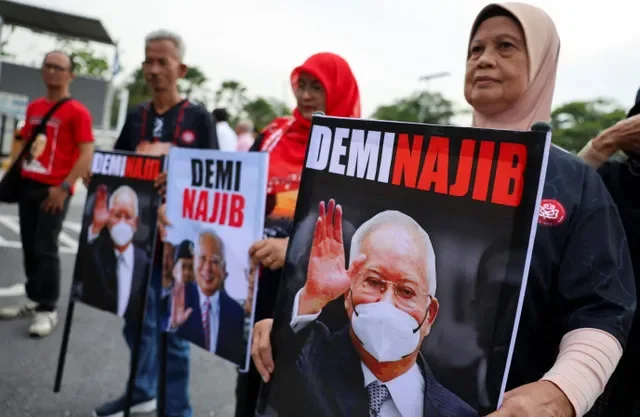 Apoiadores do ex-primeiro-ministro da Malásia Najib Razak seguram faixas com seu retrato em frente ao Palácio da Justiça, em Putrajaya, Malásia, em 26 de dezembro de 2025. REUTERS/Hasnoor Hussain