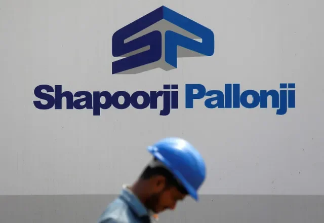 صورة أرشيفية: عامل بناء يمر بجانب لوحة إعلانية لمجموعة Shapoorji Pallonji الهندية على مشارف مومباي، الهند، 17 أبريل 2018.