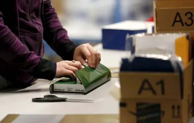 FILE PHOTO: A worker gift wraps a holiday order for a customer at the Amazon Fulfillment Center in Tracy, California, November 29, 2015. REUTERS/Fred Greaves/File Photo