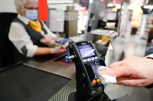 A customer disinfects the number entry pad before paying cashless at the Edeka grocery store in Duesseldorf, Germany, April 29, 2020. REUTERS/Wolfgang Rattay