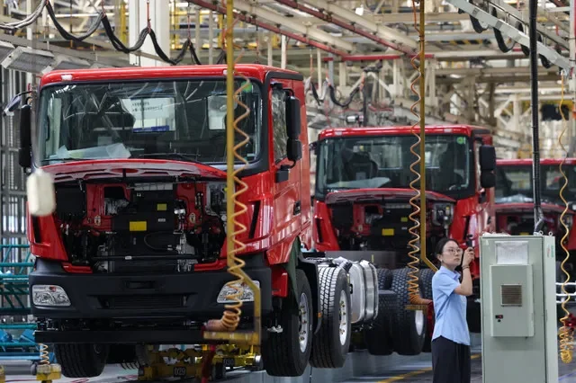 A woman films next to a truck assembly line at Beiben Trucks Group factory during an organised media tour, in Baotou, Inner Mongolia Autonomous Region, China, June 13, 2026. REUTERS/Maxim Shemetov
