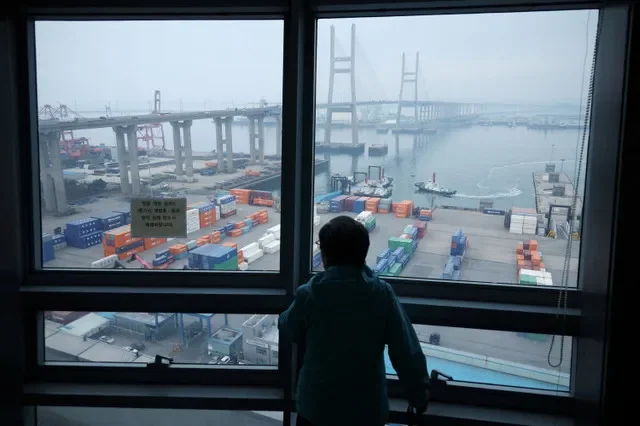 A woman looks at cranes and shipping containers from an observation platform at Pyeongtaek port in Pyeongtaek, South Korea, April 2, 2025. REUTERS/Kim Hong-Ji