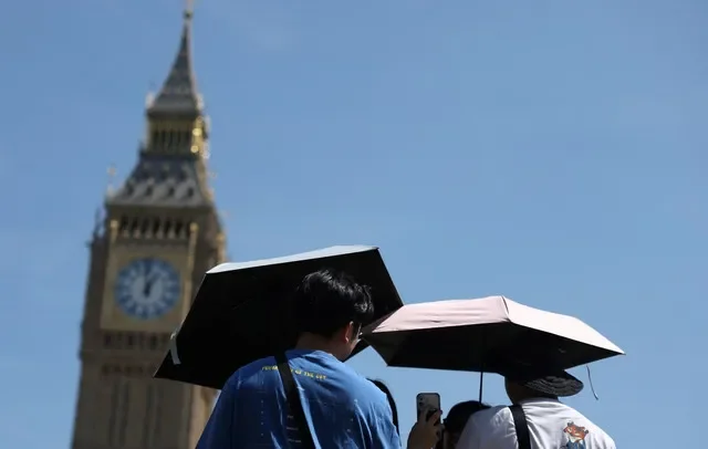 Người dân dùng ô che nắng gần Tháp Elizabeth, thường được gọi là Big Ben, và Tòa nhà Quốc hội, giữa lúc cảnh báo sức khỏe do nắng nóng và điều kiện thời tiết hạn hán tiếp diễn tại Luân Đôn, Anh, ngày 3 tháng 8 năm 2026. REUTERS/Toby Melville
